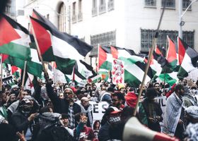 Protesters holding Palestinian flags in a demonstration outdoors, displaying unity and political activism.